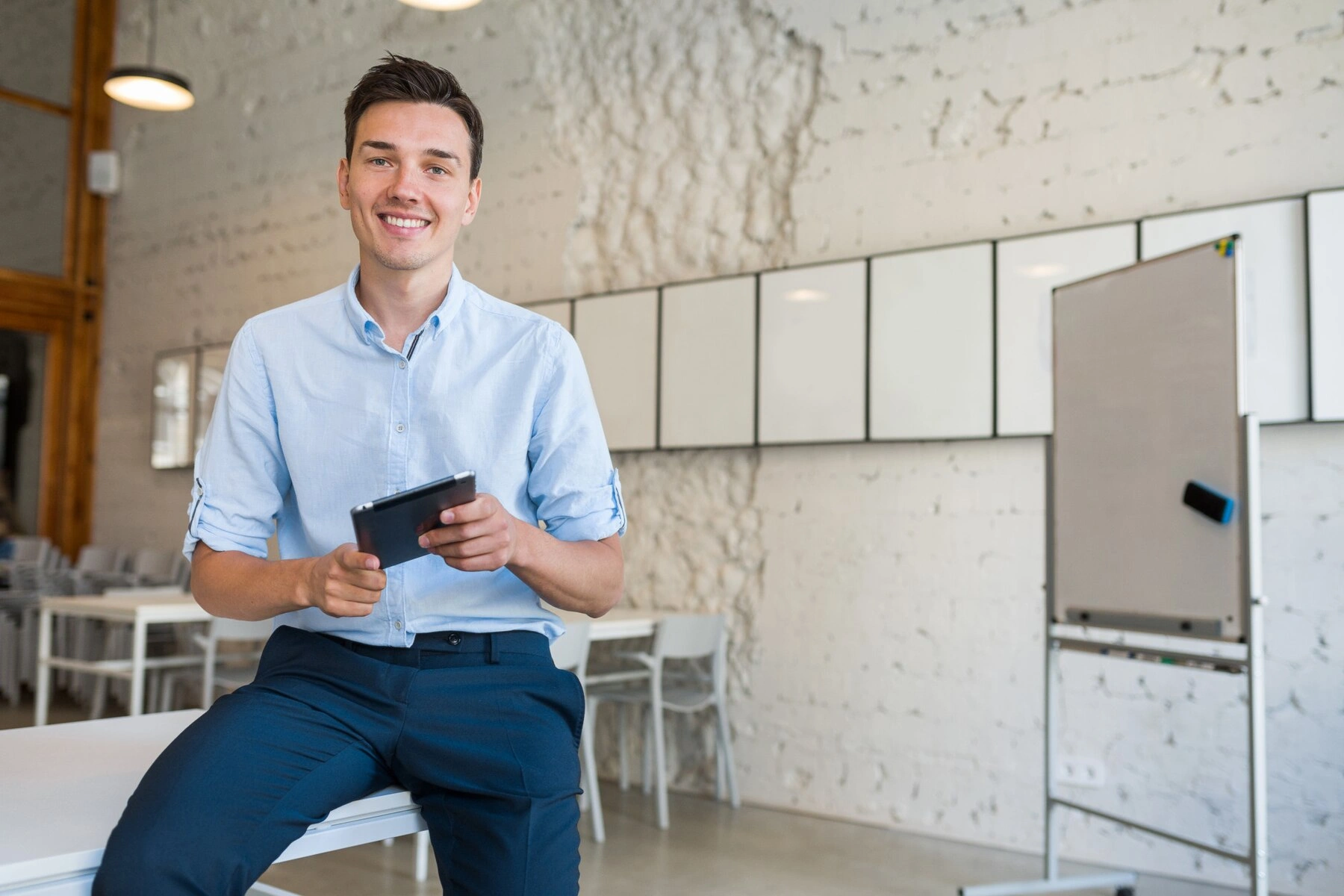 Smiling business owner holding a tablet in a modern office, preparing to discuss business payment strategies.